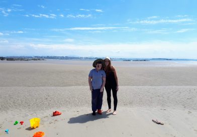 The picture shows two people enjoying the sun on Cymyran beach for free